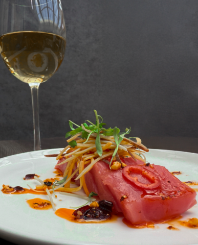 An appetizer dish of Tuna Crudo with Salsa Macha, Fresno Chiles, Carrot, and Lime
